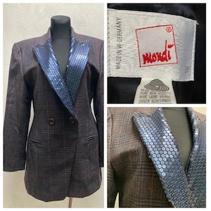 May include: A brown and black plaid blazer with a double-breasted closure and a blue sequined collar. The label reads "moxdi" and "MADE IN W-GERMANY".