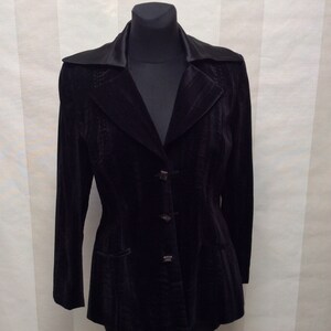 May include: A black velvet blazer with a satin collar and four buttons. The blazer has a fitted waist and a slightly flared hem.