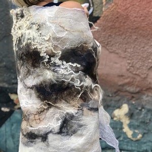 May include: A white and black wool shawl with a unique, abstract design. The shawl is made of soft, flowing fabric and has a delicate, ethereal look.