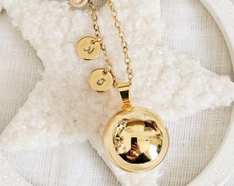 Customizable gold pregnancy bola with engraving of parents' initials on round tassels or hearts on stainless steel chain.