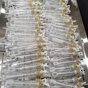 May include: A tray of clear plastic bubble wands with gold glitter and heart-shaped handles. The wands are arranged in rows on a silver tray.