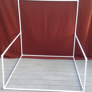May include: White PVC pipe frame for a photography backdrop. The frame is assembled into a rectangular shape with four vertical supports and two horizontal supports.