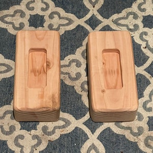 May include: Two wooden blocks with a rectangular cutout in the center. The blocks are light brown and have a smooth finish.