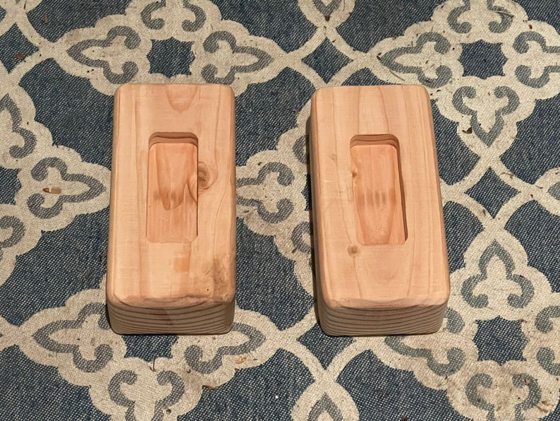 May include: Two wooden blocks with a rectangular cutout in the center. The blocks are light brown and have a smooth finish.
