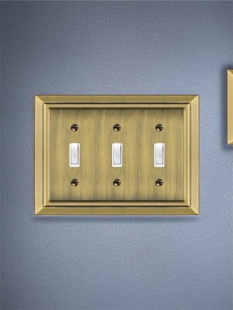 May include: A brass wall plate with three toggle switches. The plate has a decorative border and a brushed finish.