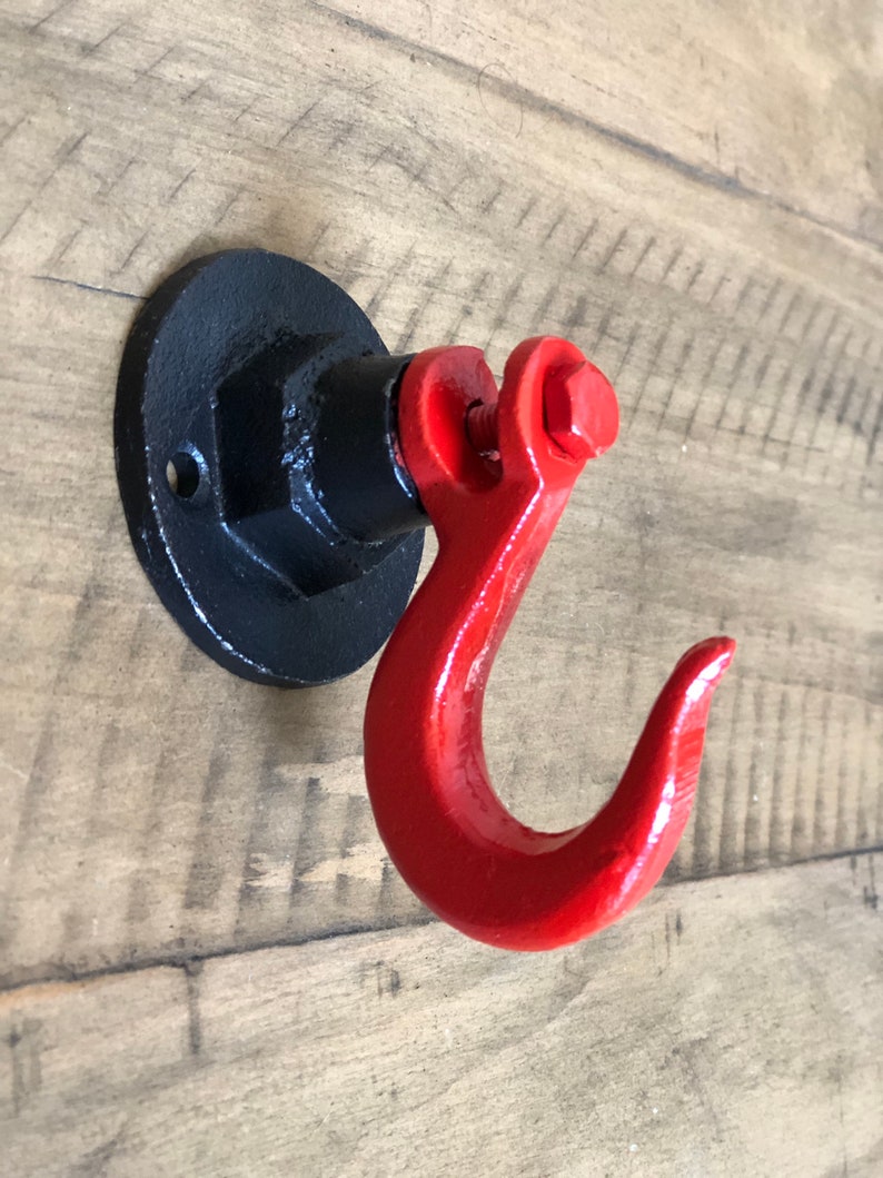May include: A black metal hook with a red painted hook. The hook is attached to a black metal base.