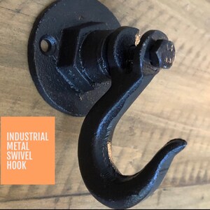 May include: Black metal swivel hook with a round base and a large hook. The hook is attached to a metal plate with a screw.  INDUSTRIAL METAL SWIVEL HOOK is written on a peach-colored rectangle.