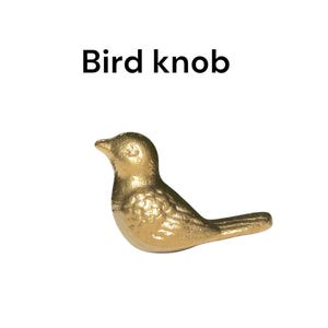 May include: A gold bird-shaped cabinet knob. The bird is facing right and has a detailed design.