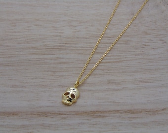 May include: A gold chain necklace with a small, detailed skull pendant.