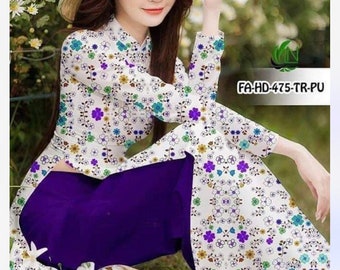 May include: A woman wearing a white dress with a floral pattern and a purple skirt. She is wearing a traditional Vietnamese conical hat and is holding a bouquet of white flowers.