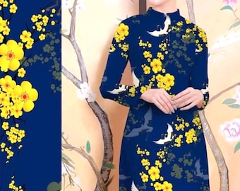 May include: A blue long-sleeved dress with a high neck and a floral pattern featuring yellow flowers and white cranes. The dress has a traditional Vietnamese style.