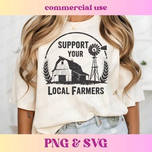 May include: A white t-shirt with a black graphic design featuring a barn, windmill, and wheat stalks. The text "Support Your Local Farmers" is printed below the graphic.