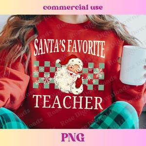 Puede incluir: Sudadera roja con un gr&aacute;fico blanco que dice "El favorito de Santa Maestro" con una ilustraci&oacute;n de estilo vintage de Santa Claus. La sudadera tiene un patr&oacute;n a cuadros con copos de nieve.