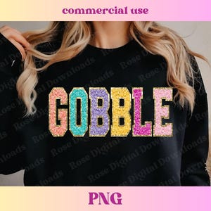 Peut inclure: Sweat-shirt noir avec le mot "GOBBLE" en lettres pailletées arc-en-ciel. Les lettres sont soulignées de noir.
