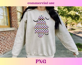 May include: A light beige sweatshirt with a checkered ghost graphic in pink, orange, and blue. The ghost has two black eyes and is surrounded by black bats.