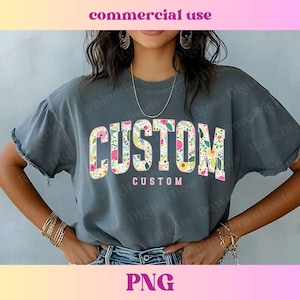 Peut inclure: Un t-shirt gris avec un motif floral qui dit "CUSTOM" en lettres roses et blanches.