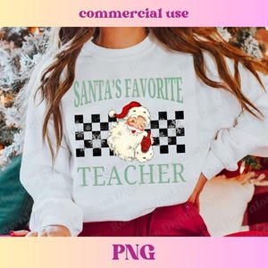 Puede incluir: Sudadera blanca con un dise&ntilde;o a cuadros verde y negro, un Pap&aacute; Noel de dibujos animados y el texto "El profesor favorito de Pap&aacute; Noel".