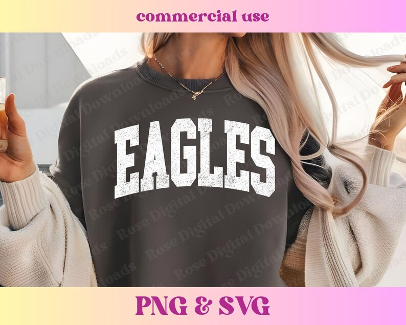 以下が含まれることがあります： 暗いグレーのトレーナーに、白で「EAGLES」という文字がヴィンテージ風のダメージ加工でプリントされています。