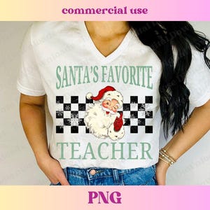 Puede incluir: Camiseta blanca con un dise&ntilde;o a cuadros verde y blanco y una imagen de dibujos animados de Santa Claus. El texto "Santa's Favorite Teacher" est&aacute; impreso en la camiseta.