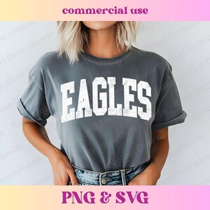 以下が含まれることがあります： 前面に白い「EAGLES」の文字がプリントされたグレーのTシャツ。文字は使い古したようなヴィンテージ風です。