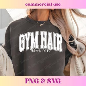 Peut inclure: Un sweat-shirt gris fonc&eacute; avec le texte "GYM HAIR don't care" en lettres blanches. Le sweat-shirt est port&eacute; par une personne aux longs cheveux blonds.
