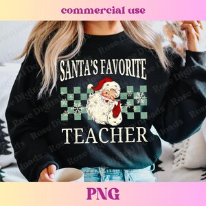 Puede incluir: Sudadera negra con un patr&oacute;n de cuadros blancos y verdes, una imagen de dibujos animados de Pap&aacute; Noel y el texto "El profesor favorito de Pap&aacute; Noel".