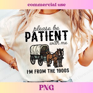 May include: A white t-shirt with the text "Please be PATIENT with me I'M FROM THE 1900S" in black. The design also includes a cartoon image of a horse-drawn wagon.