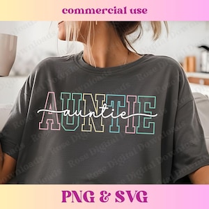 Peut inclure: Un t-shirt gris avec le mot "AUNTIE" en lettres colorées soulignées. Le mot "auntie" est écrit en cursive sous les lettres.