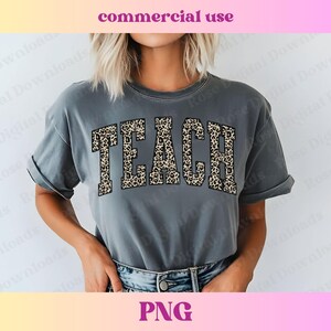 Peut inclure: Un t-shirt gris avec le mot "TEACH" imprim&eacute; en imprim&eacute; l&eacute;opard. Les lettres sont soulign&eacute;es de noir.