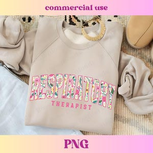 May include: A light gray sweatshirt with the text "RESPIRATORY THERAPIST" in pink letters with a floral pattern. The letters are in a bold, blocky font.
