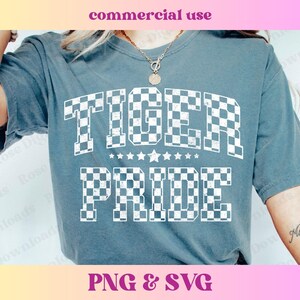 May include: A blue t-shirt with a white checkered design that says "TIGER PRIDE" in a vintage style font.