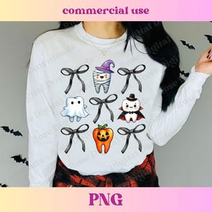 Peut inclure: Chemise blanche à manches longues avec un motif de six dents sur le thème d'Halloween. Les dents sont habillées en fantôme, en momie, en vampire, en citrouille et deux avec des nœuds. Le motif est centré sur la chemise.