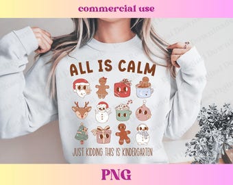 Könnte beinhalten: Ein weißer Pullover mit dem Text "ALL IS CALM JUST KIDDING THIS IS KINDERGARTEN" in braunen Buchstaben. Der Pullover zeigt verschiedene Comic-Illustrationen von weihnachtlichen Figuren, darunter einen Schneemann, ein Rentier, einen Lebkuchenmann und einen Weihnachtsbaum.