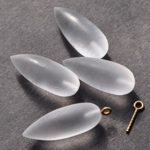 May include: Four clear glass teardrop-shaped beads and a gold jump ring with a gold eye pin.