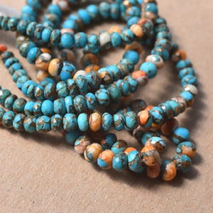 May include: Strands of turquoise and orange gemstone beads. The beads have a faceted cut and are strung together. The beads are a mix of blue, orange, and white colors. The beads are likely used for jewelry making.