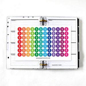 May include: A sheet of rainbow coloured dollar sign stickers. The stickers are arranged in a grid pattern and are perfect for use in a planner or journal.
