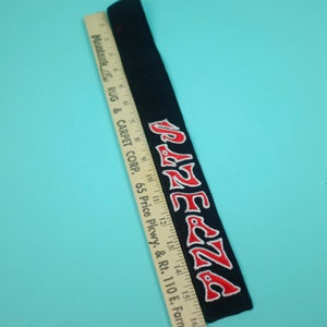 May include: Black embroidered patch with the word "PAZECZA" in red letters with white trim. A wooden ruler with inch measurements is next to the patch. The patch is approximately 16 inches long.