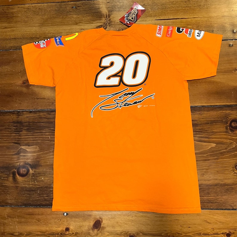Op de afbeelding: Oranje t-shirt met het nummer 20 in wit met een zwarte omlijning en een zwarte handtekening. Het shirt heeft sponsorlogo's op de mouwen en een aangehecht label.