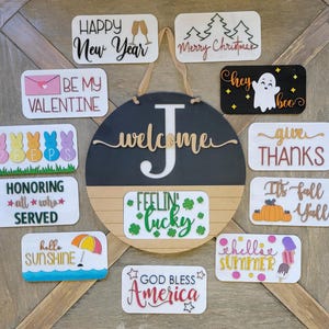 May include: A collection of 12 wooden signs with various holiday and seasonal greetings. The signs are painted in different colours and feature festive designs, such as a ghost, a snowman, a shamrock, and a pumpkin. The signs are perfect for decorating a home or business for any occasion.
