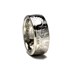 May include: A silver ring made from a 1942 half dollar coin. The ring features the inscription "HALF DOLLAR" and the year "1942" on the side.