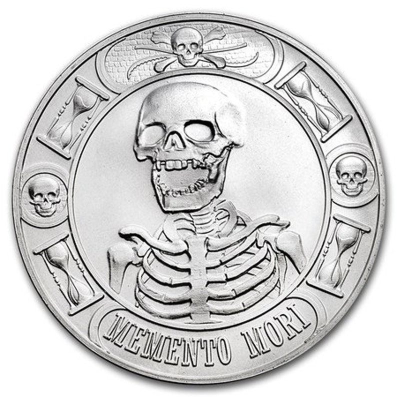 May include: A silver round coin with a skull and crossbones design. The coin features a skeleton with the words "Memento Mori" inscribed around the edge.