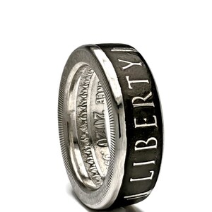 May include: A silver ring made from a 2020 American Silver Eagle coin. The ring is black on the outside with the word "LIBERTY" engraved in white lettering. The inside of the ring shows the coin's original design.