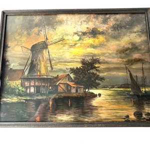 May include: A framed oil painting depicting a windmill on a riverbank at sunset. The windmill is a dark brown color with white sails. The river is a golden color and there are two sailboats in the distance. The sky is a mix of pink, orange, and yellow.