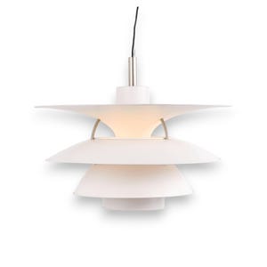 May include: White pendant light fixture with a tiered, layered design. The light has a series of curved, disc-shaped shades, suspended from a silver-colored stem and a black cord. The light is turned on, illuminating the interior.