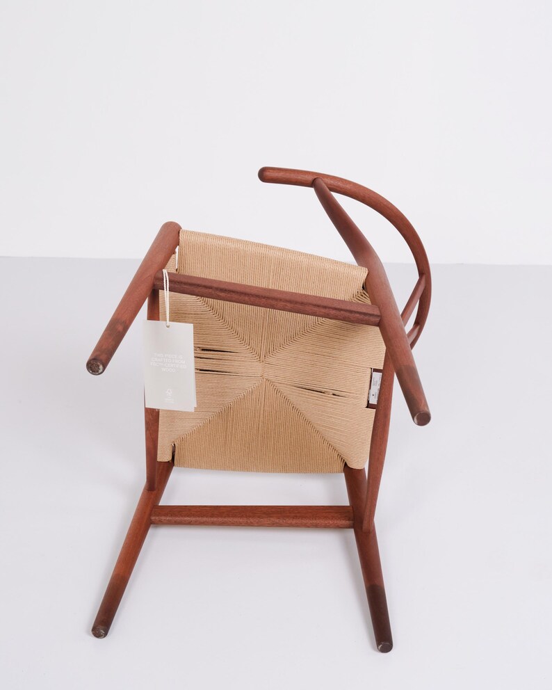 May include: A wooden chair with a woven seat and back. The chair has a curved backrest and four legs. The wood is a warm brown color, and the woven seat is a light tan. A tag hangs from the chair.