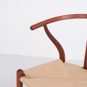 May include: A wooden chair with a curved back and woven seat. The chair's frame is a rich brown color, and the seat is made of a light tan woven material. The chair has a classic, minimalist design.
