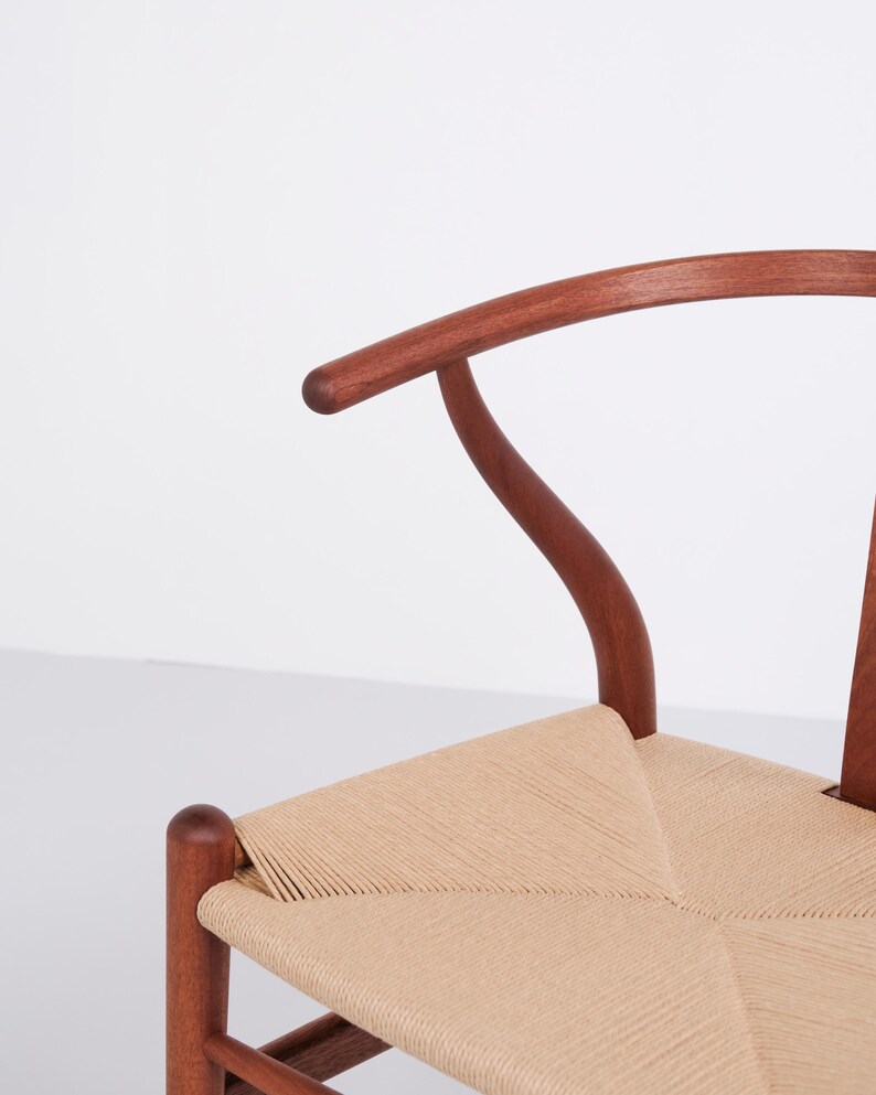 May include: A wooden chair with a curved back and woven seat. The chair's frame is a rich brown color, and the seat is made of a light tan woven material. The chair has a classic, minimalist design.