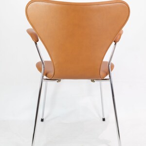 Puede incluir: Una silla de cuero marr&oacute;n con patas y brazos cromados. La silla se ve desde atr&aacute;s.