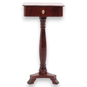Op de afbeelding: Een donkerbruine houten zuiltafel met een rechthoekig blad en een enkele lade. De lade is voorzien van een klein, centraal geplaatst koperen sleutelgatbeslag. De tafel wordt ondersteund door een centrale gedraaide kolom en een driepootvoet.