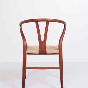 May include: A wooden chair with a curved back and woven seat. The chair's frame is a rich brown color, and the seat is made of a light tan woven material. The back of the chair has a distinctive Y-shaped design.